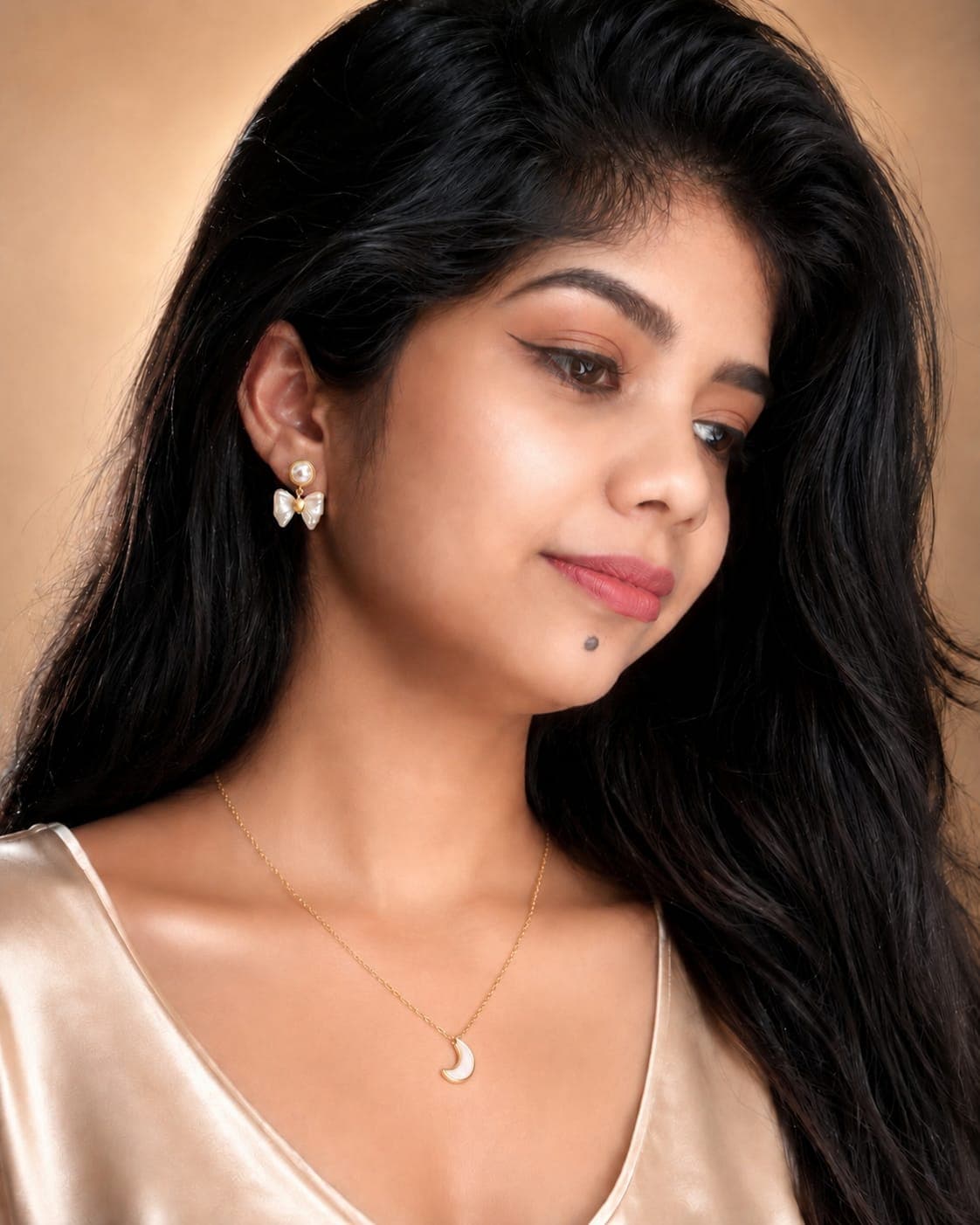 A crescent moon pendant and pearl bow earrings worn with a satin top